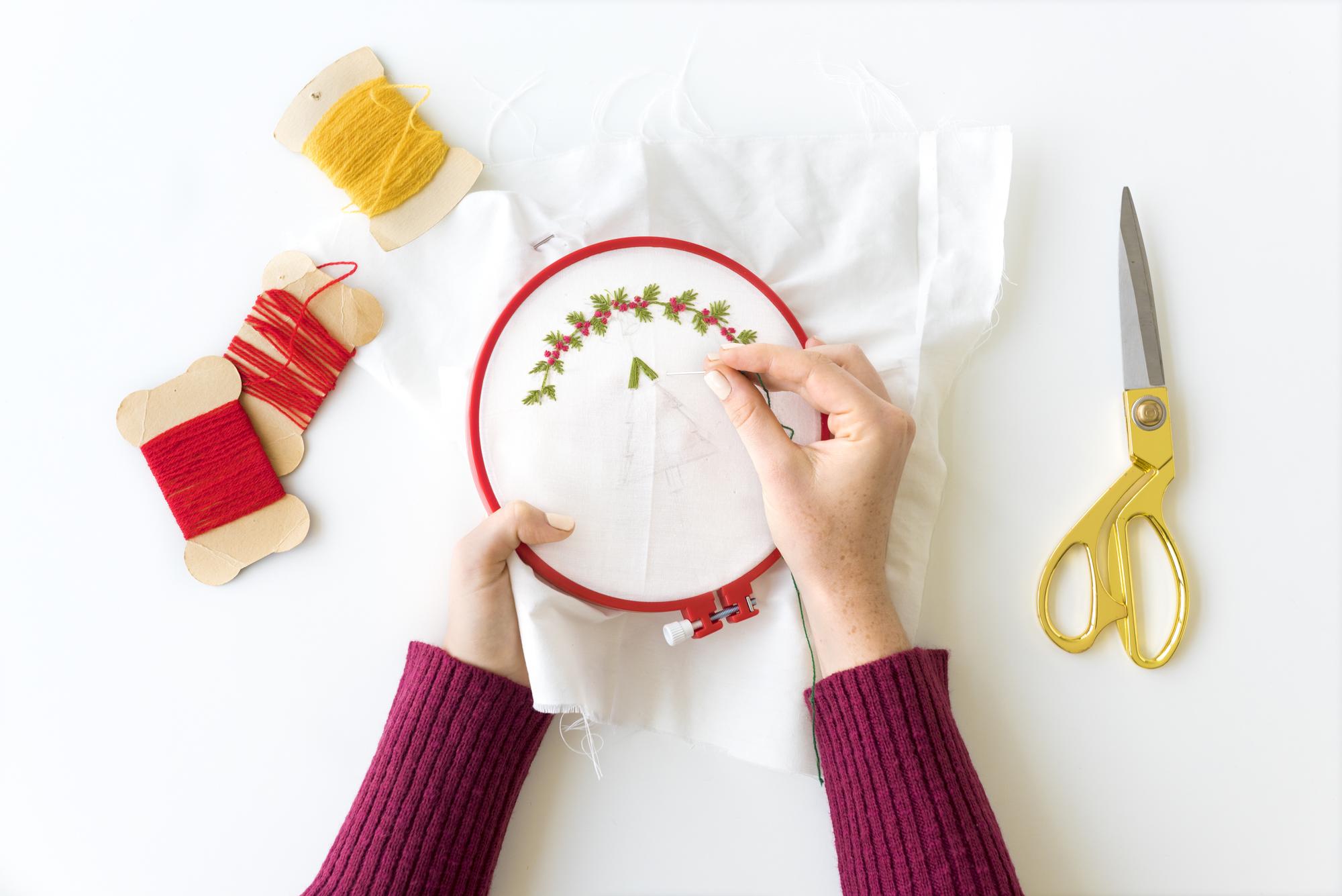 Artist arranging embroidered samples on wooden table